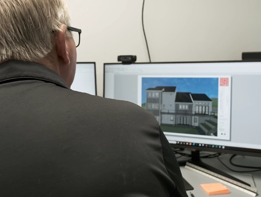 John Petsco sitting at desk looking at 3D rendering