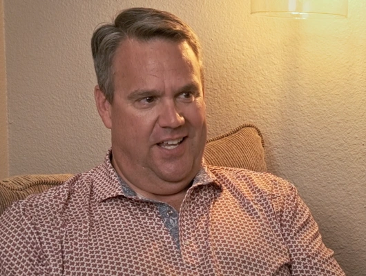 man in a red patterned shirt sitting under a lamp