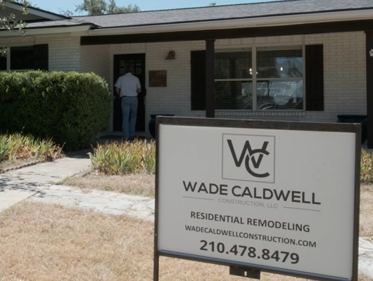 front view of a black and White House with a Wade Caldwell company sign in front