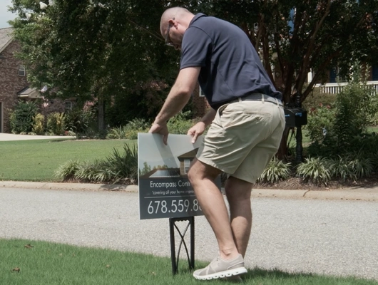 man putting branded sign into the grass