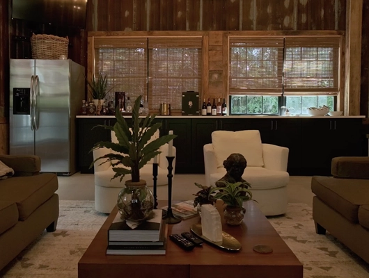 two white chairs and a coffee table with aesthetic decor inside a barn