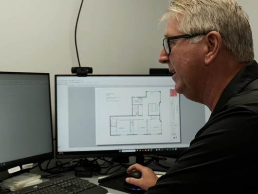 John Petsco sitting at desk looking over floorplans on computer