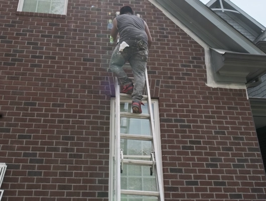 guys climbing up a ladder that is leaning against the exterior of a house