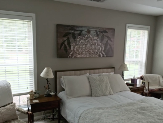 master bedroom with white sheets and painting above the bed